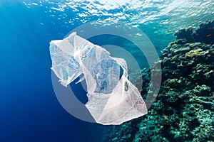 Discarded plastic bag drifting past a tropical coral reef