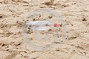 Discarded plastic water bottle lies in the sand