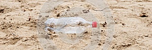 Discarded plastic water bottle lies in the sand