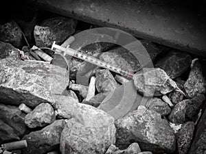Discarded syringe lying amongst stones photo