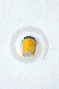 a discarded used drink cup lies in the snow