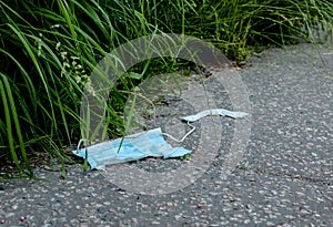 Discarded used, torn and dirty face mask on the concrete floor