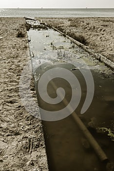 Discharge of dirty industrial wastewater in sea on city beach. Poisoning of recreation areas by spread of diseases, destruction of