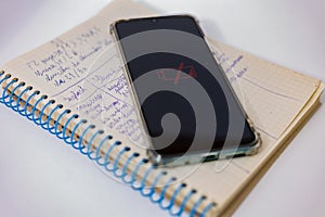 A discharged phone lies on an open notepad