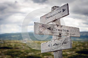 Discipline, creates and lifestyle text on wooden sign post outdoors in landscape scenery. photo