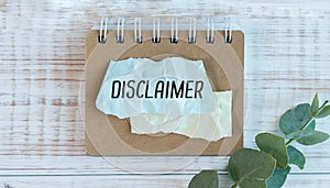 disclaimer text written on a blue piece of paper on wooden background