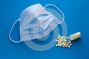 Disclosed is a medical mask on a blue background with yellow tablets. Respiratory protection