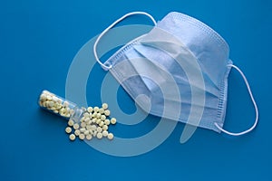 Disclosed is a medical mask on a blue background with yellow tablets. Respiratory protection