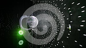 The disco ball mirror spins and reflects the light at the disco in the club.