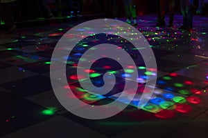 Disco on dance floor. Flower spots on floor. Color music indoors