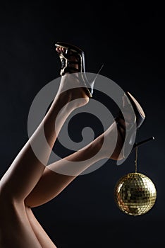 Disco party event. Woman legs with gold disco ball. Celebrate concept. Gold disco ball on high heels. Party concept.