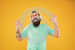 Disco sound. Bearded man relaxing with melodious sound on yellow background. Hipster wearing earphones playing