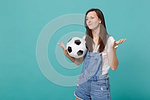 Disconcerted displeased young woman football fan support favorite team with soccer ball spreading hands isolated on blue