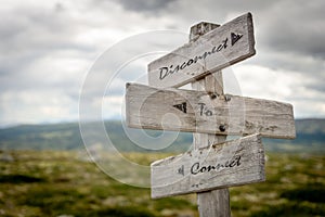 Disconnect to connect text on wooden signpost outdoors in nature.