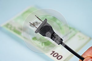 Disconnected American type electrical plug against the background of European cash money
