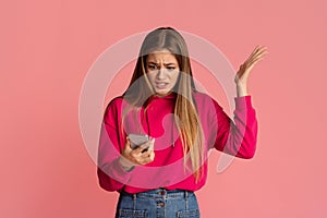 Discontent and indignation. Girl looks at smartphone and picks up hand