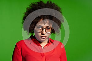 Discontent serious young African-American girl in glasses and red shirt