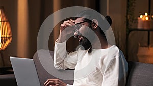 Discontented Indian Man with Laptop in the Evening Living Room