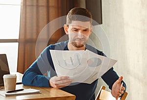 Discontented Office Worker Looking At Documents Sitting In Modern Office