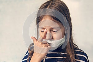 Discontented sad girl in a protective mask on her face is sad because of inability to go out on street during covid 19