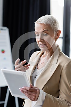 discouraged businesswoman gesturing near digital tablet