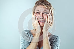 Discouraged young blond woman in pain expressing her sadness