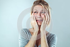 Discouraged young blond woman in pain expressing her sadness photo