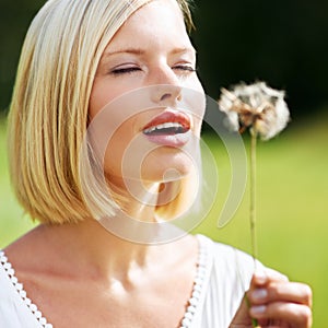 Discovering the whimsical side of nature. Cute young woman preparing to blow at a dandelion.