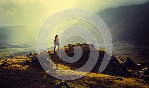 Discovery Travel Destination Concept. Hiker Woman With Backpack Rises To The Mountain Top Against Backdrop Of Sunset Vintage Toned photo