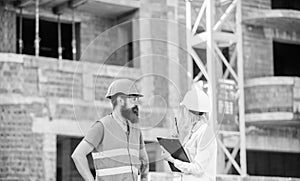 Discuss progress project. Safety inspector concept. Woman inspector and bearded brutal builder discuss construction