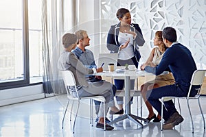 Discussing business in detail. a team of businesspeople working on a laptop together at a table in the office.