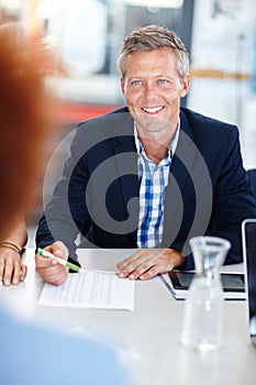 Discussing a new deal. A mature male manager sitting in a meeting with his team.