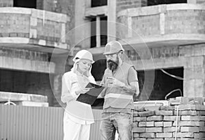 Discussing plan. Woman engineer and builder communicate at construction site. Construction team communication concept