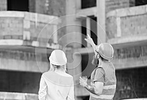 Discussing plan. Woman engineer and builder communicate at construction site. Relationships between construction clients