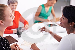 Discussing the plans. A group of female architects working together on a project at a conference table.