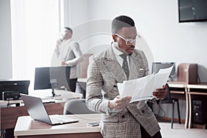 Discussing a project. Two black business people in formalwear discussing something while one of them pointing a paper