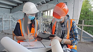 Discussion of construction work between a female engineer and a male foreman in medical masks on the construction site.