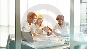 Discussion scene of engineers, house architect, construction engineers in the sunlight meeting room with the blueprint and