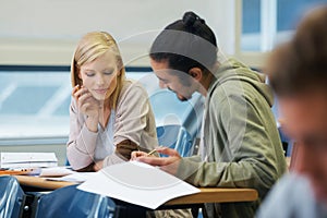Discussion, university and students in classroom for studying with text book for test or exam. Conversation, writing and