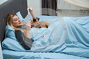 Ill woman with fever and her pet in bedroom