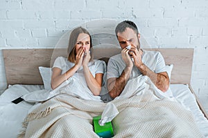 diseased husband and wife sneezing while