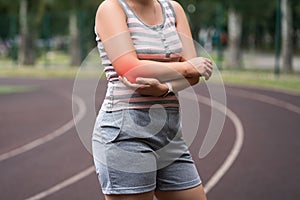 Diseases of the elbow joint, bone fracture and inflammation, tendon injury, athletic woman on a running track after workout
