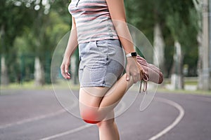 Diseases of the knee joint, bone fracture and inflammation, athletic woman on a running track after workout suffering from pain in