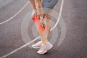 Diseases of the knee joint, bone fracture and inflammation, athletic woman on a running track after workout suffering from pain in