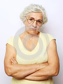 The disgruntled grandmother looks up and condemns. An elderly woman stands with her arms crossed over her chest. photo