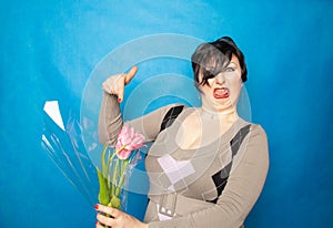 Disgruntled woman with a bouquet of flowers emotionally shows hatred and disgust for cut flowers. the concept of ecology