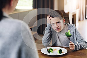 Disgust, food and child with vegetables in home for nutrition, health and cooking. Lunch, angry and dinner with boy and