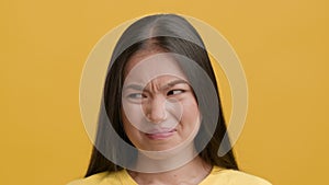 Disgusted Asian Woman Frowning Feeling Bad Smell Over Yellow Background