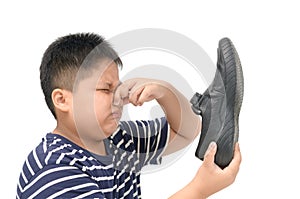 Disgusted boy holding a pair of smelly leather shoes