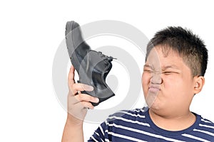 Disgusted boy holding a pair of smelly leather shoes